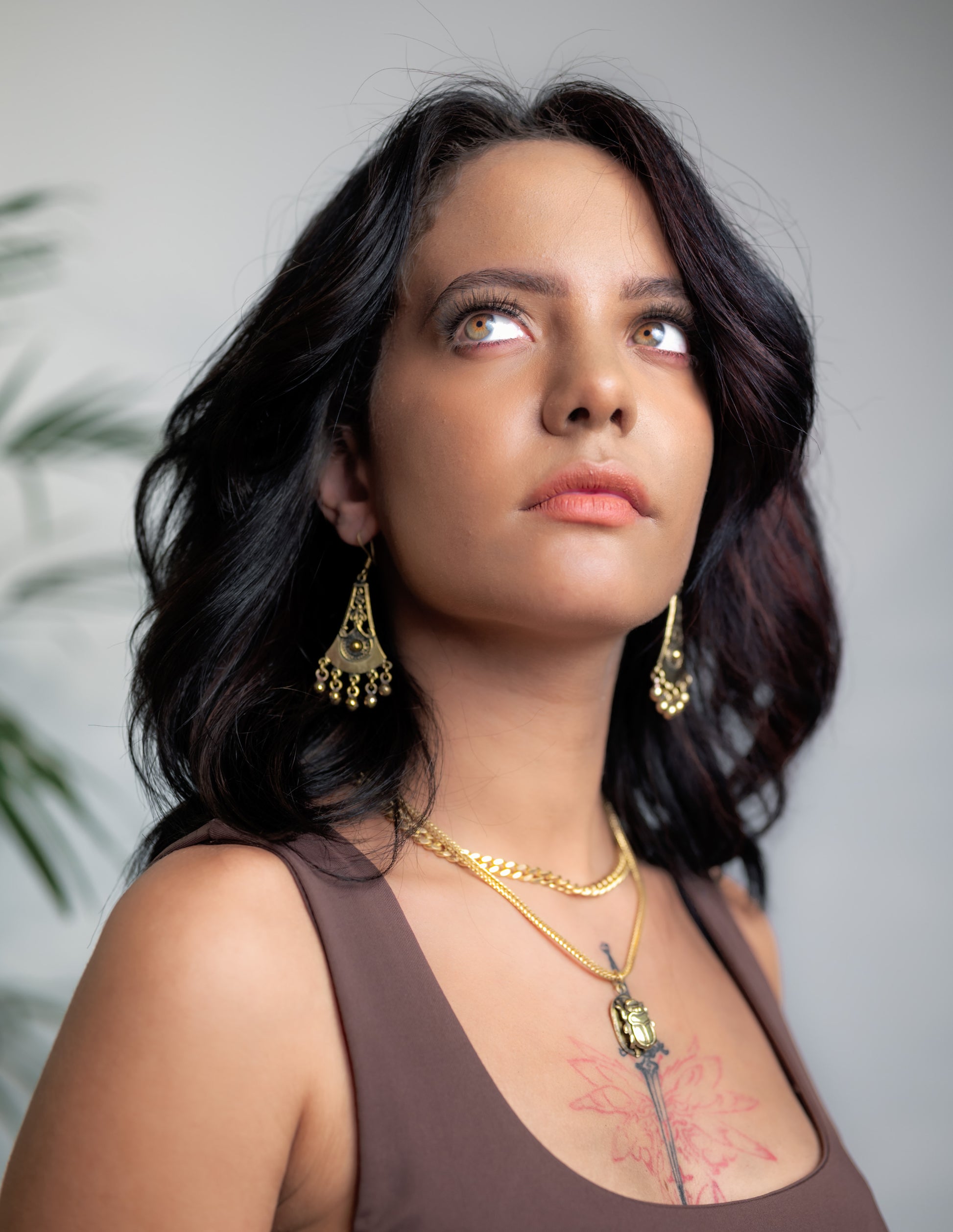 Side profile of model wearing Zahra brass necklace, showing sweeping silhouette and drape along neck